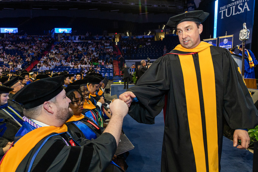 University of Tulsa professor in regalia fist-bumps graduate at commencement 2026.