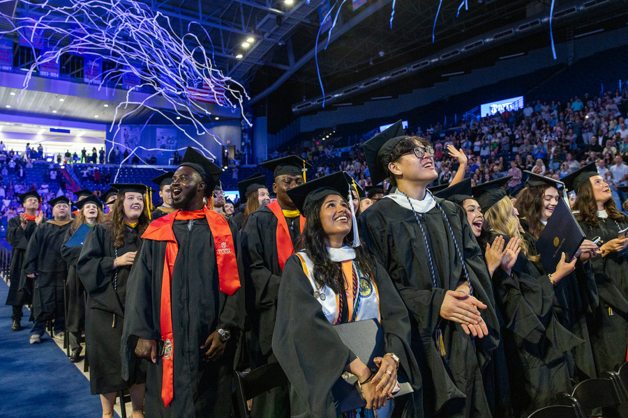 Graduates in caps and gowns celebrate commencement 2026 with confetti.