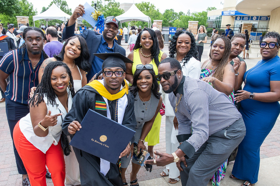 Graduates and their families celebrate at Commencement 2026 with a proud graduate holding a diploma.