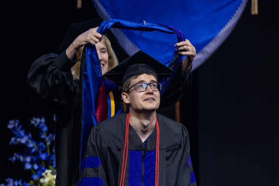 Graduate commencement 2026: A student receives his academic hood at a law ceremony.