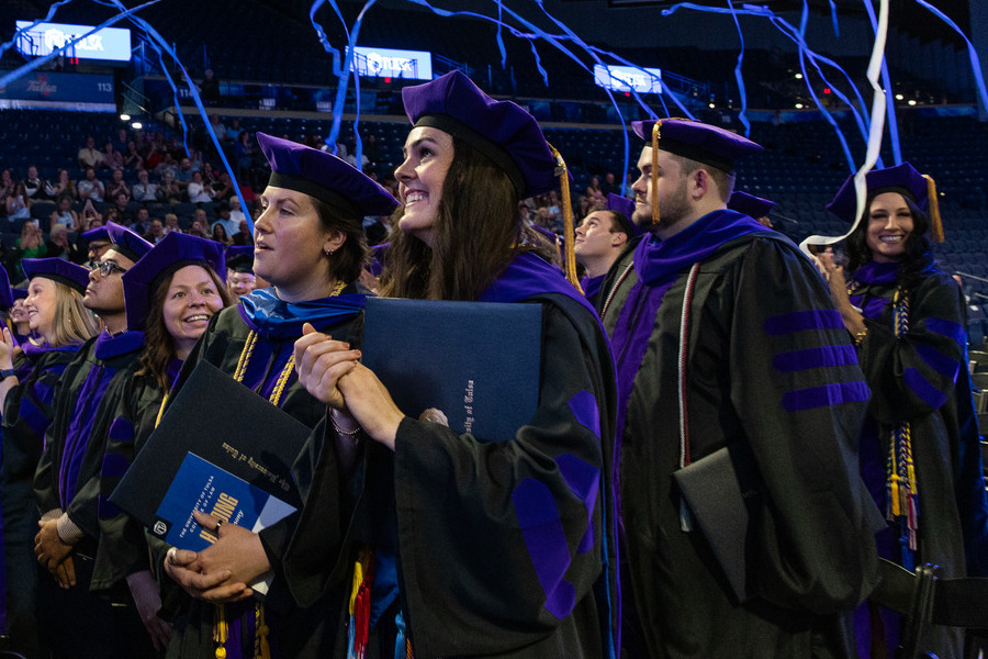 Law graduates in caps and gowns celebrating commencement 2026 with confetti.