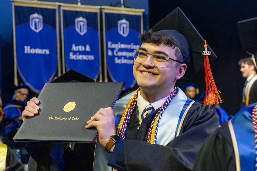 Graduate holding diploma at commencement 2026