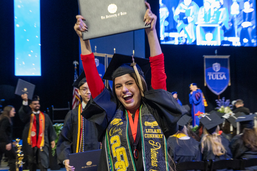 Excited graduate holds diploma at 2026 commencement ceremony