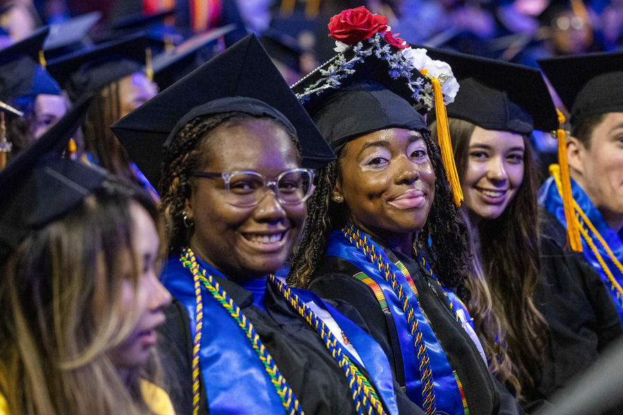 Two graduates in caps and gowns smile at commencement 2026.