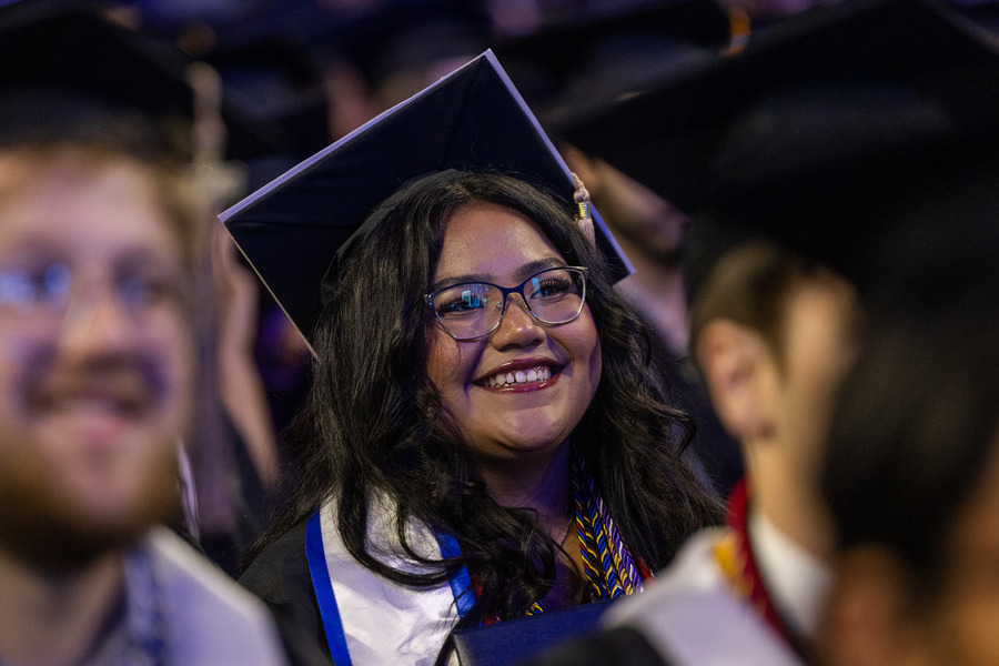 Smiling graduate in cap and gown at commencement 2026.