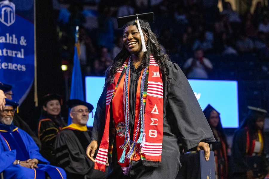 Graduate in cap and gown smiles at commencement 2026 ceremony