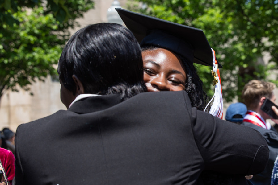 Graduate in cap and gown hugs a person at commencement 2026.