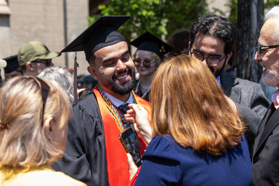 Graduate in cap and gown smiles for a photo at commencement 2026