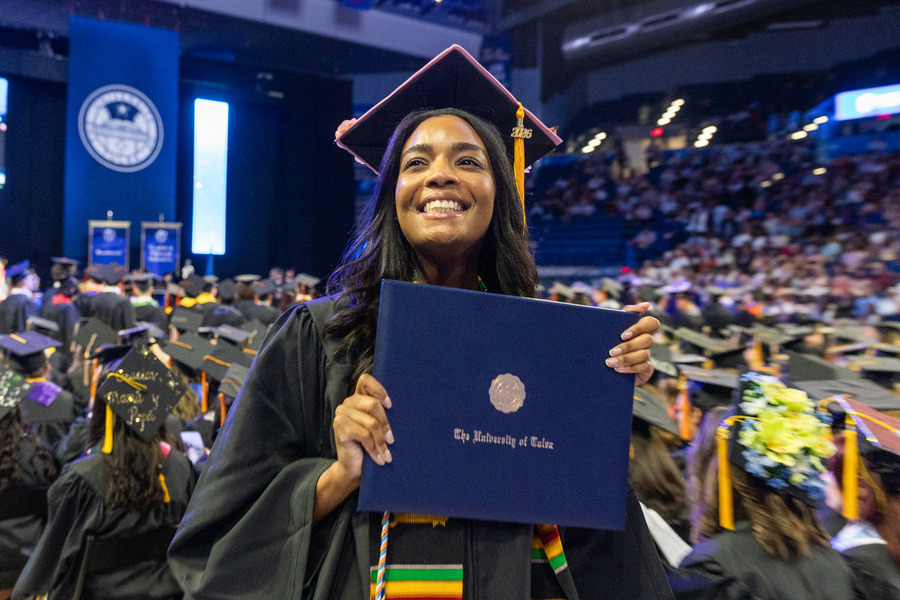 Graduate holding diploma at commencement 2026
