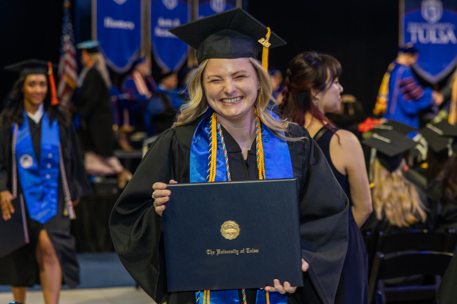 Happy graduate holding diploma at 2026 commencement ceremony.