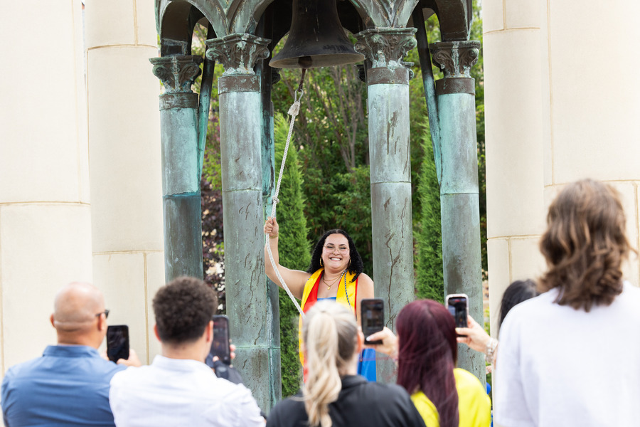 UTulsa alumna ringing the Kendall Bell in front of family and friends