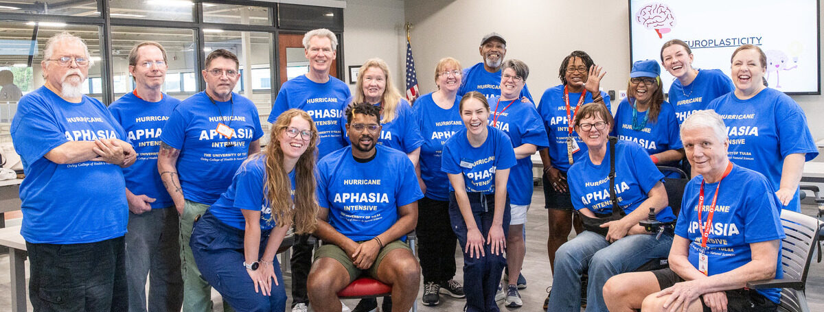 UTulsa students smiling alongside individuals at Aphasia camp wearing "Aphasia Intensive" t-shirts.