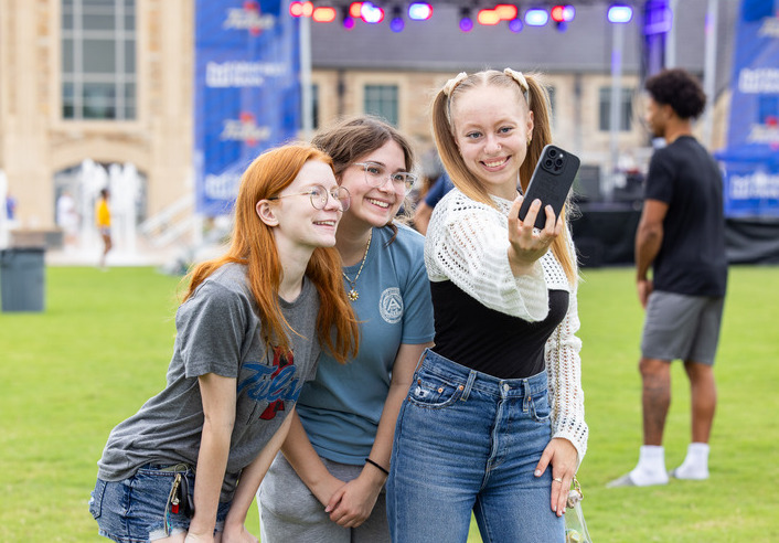 Three smiling teens take a selfie at STRETCHED.