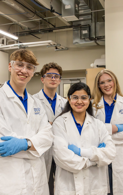 Four students in lab coats and goggles