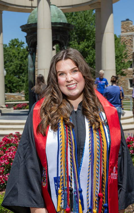 Graduate in cap and gown with colorful sashes