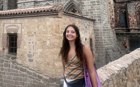 Xayda Alexander smiles in front of historic stone architecture while traveling in Spain