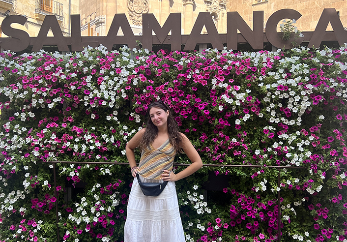 Young woman poses in front of Salamanca sign and flowers