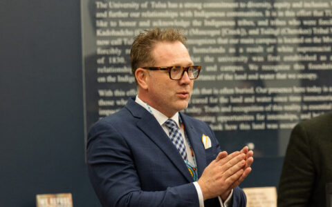 Man in suit speaking with hands clasped