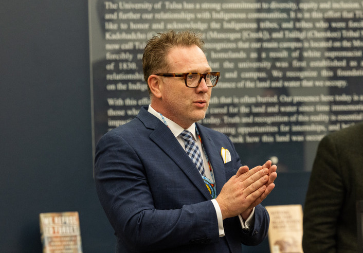 Man in suit speaking with hands clasped