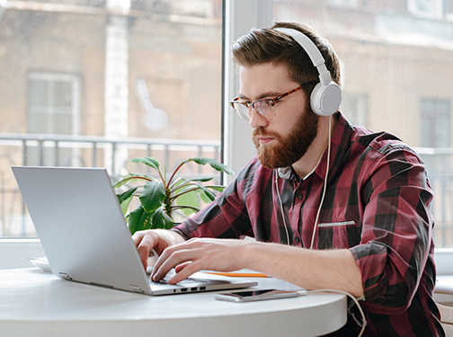 Man wearing headphones working on laptop at table