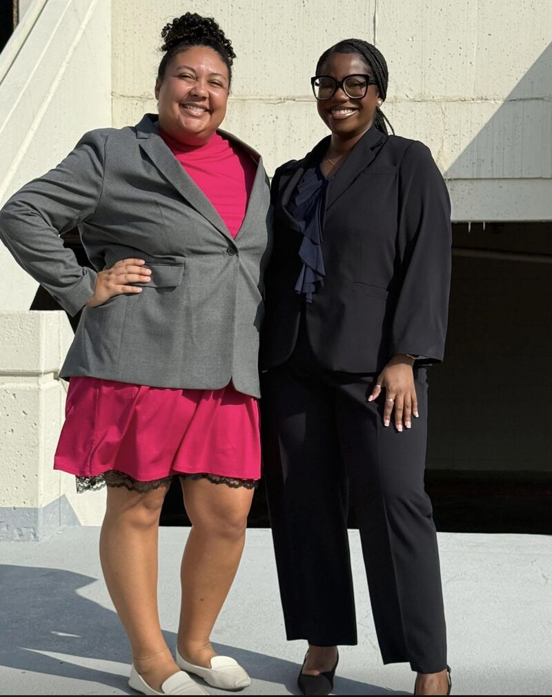 Two women in suits smiling
