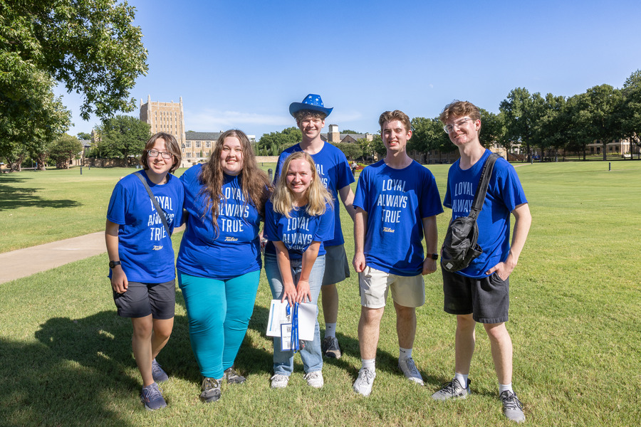 Six students in blue shirts on campus