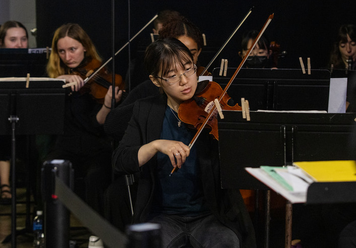 Student plays violin in orchestra