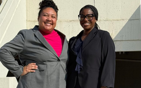 Two women in suits smiling