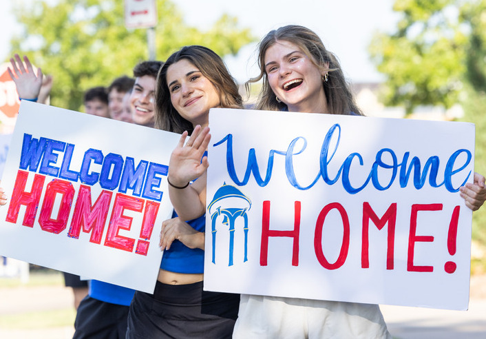 Students welcome people home with signs