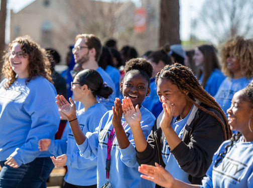 UTulsa students in blue shirts clapping and smiling