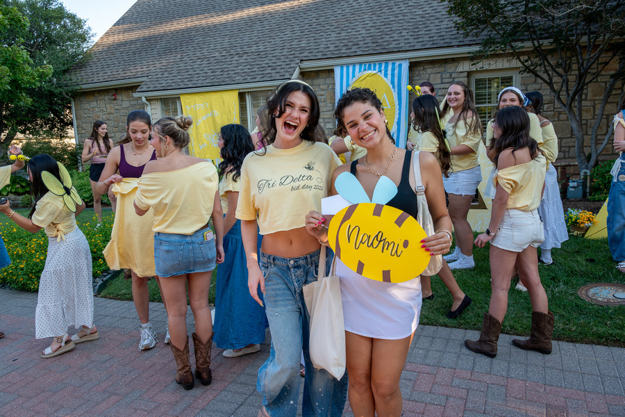 Tri Delta active poses with a new recruit, holding a bee poster