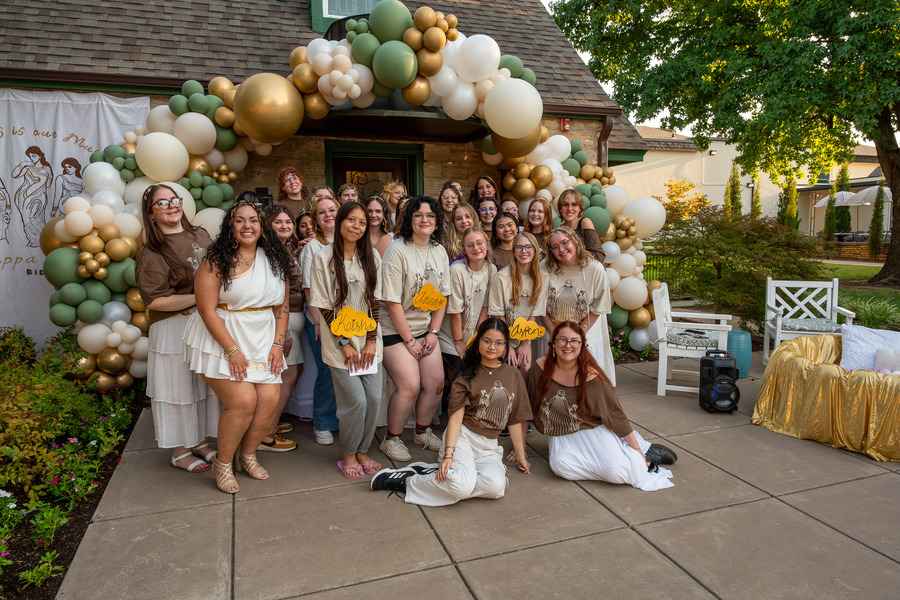 Kappa Delta sorority poses outside their house underneath a balloon arch
