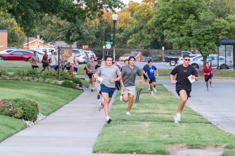 A group of young men run to their new fraternity