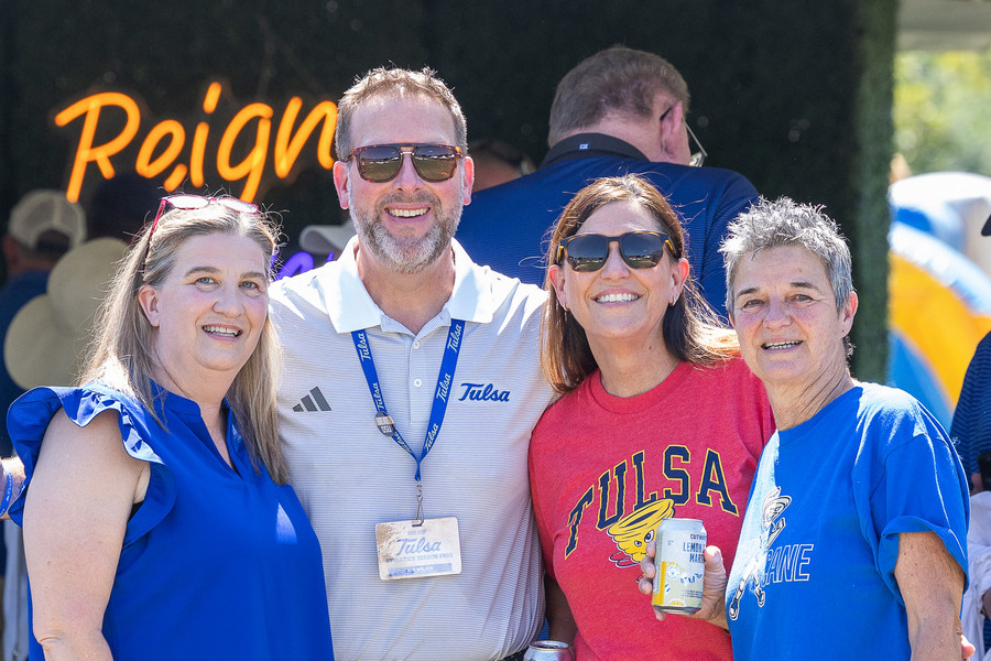 Four people in Tulsa gear smiling at the football tailgate