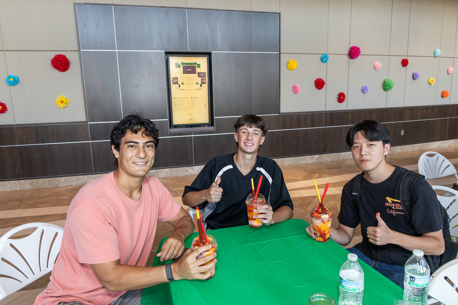 Three young men sit at a table with drinks.
