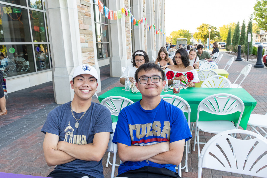 Two smiling young men sitting outside at Festival de las Flores.
