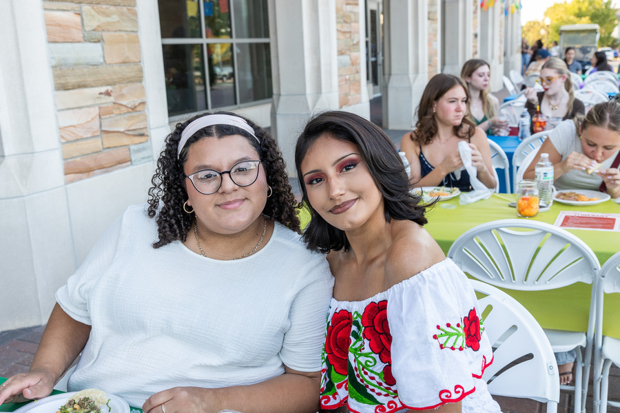 Two young women sit outside at Festival de las Flores