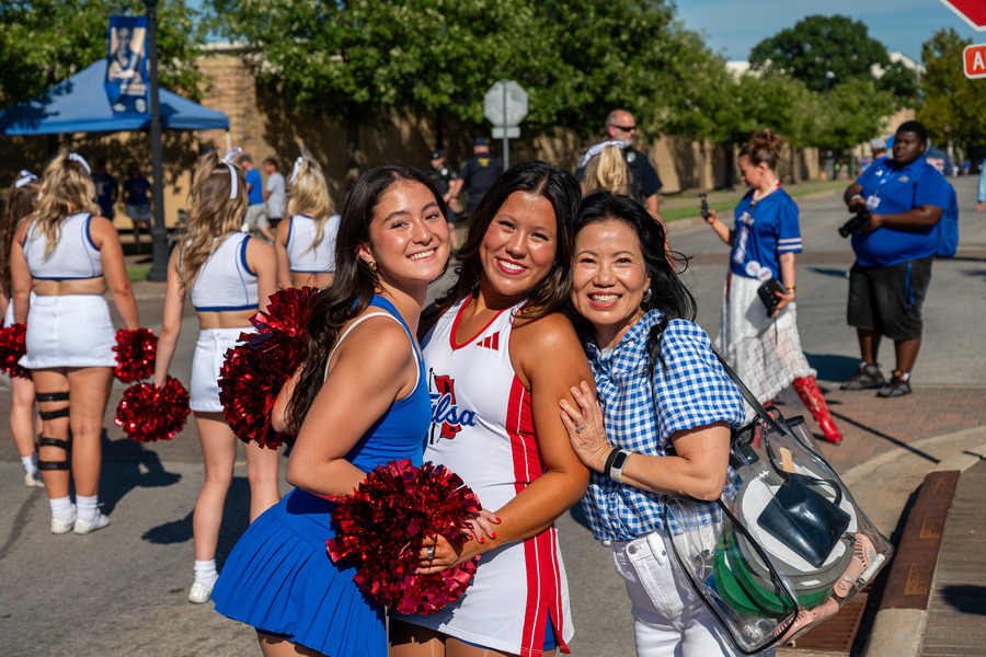 Three smiling women in Tulsa colors at the football tailgate